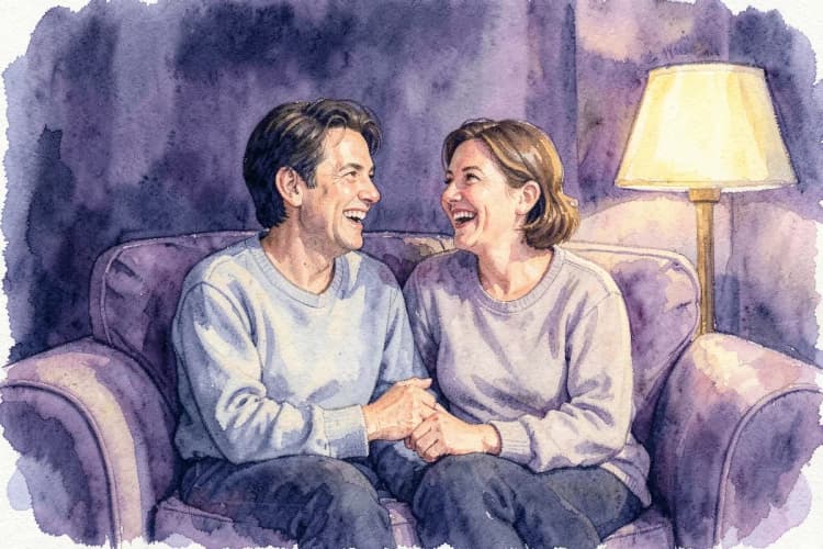 Um casal conversando e rindo em um sofá aconchegante.