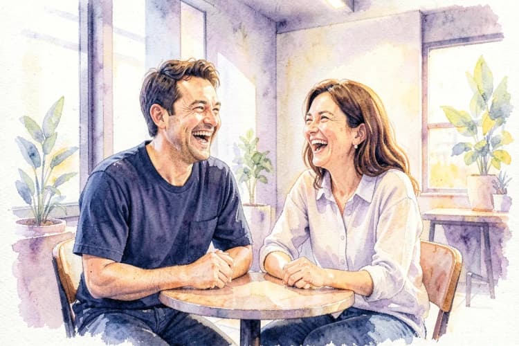 Um homem e uma mulher rindo juntos em um café aconchegante.